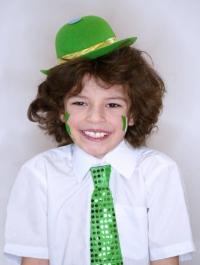 İspanyol çocuk çocuk eğleniyor Saint Patrick kutlamalar sırasında hafif bir arka plan üzerinde. Yanağımın üstünde Yeşil yonca ve İrlanda bayrağı bir çocuk gülümsüyorum. Aziz Patrick günü kutlamaları.