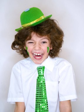 İspanyol çocuk çocuk eğleniyor Saint Patrick kutlamalar sırasında hafif bir arka plan üzerinde. Yanağımın üstünde Yeşil yonca ve İrlanda bayrağı bir çocuk gülümsüyorum. Aziz Patrick günü kutlamaları.