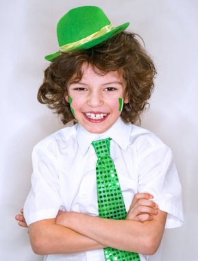 İspanyol çocuk çocuk eğleniyor Saint Patrick kutlamalar sırasında hafif bir arka plan üzerinde. Yanağımın üstünde Yeşil yonca ve İrlanda bayrağı bir çocuk gülümsüyorum. Aziz Patrick günü kutlamaları.