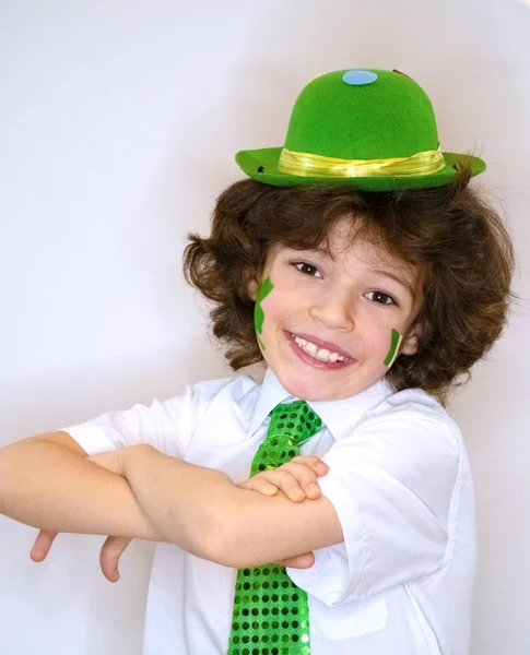 Hispanic child boy having fun during Saint Patrick celebrations over a light background. I am smiling a boy with a green shamrock and Irish flag on my cheek. Patrick's Day celebrations. — Stock Photo, Image