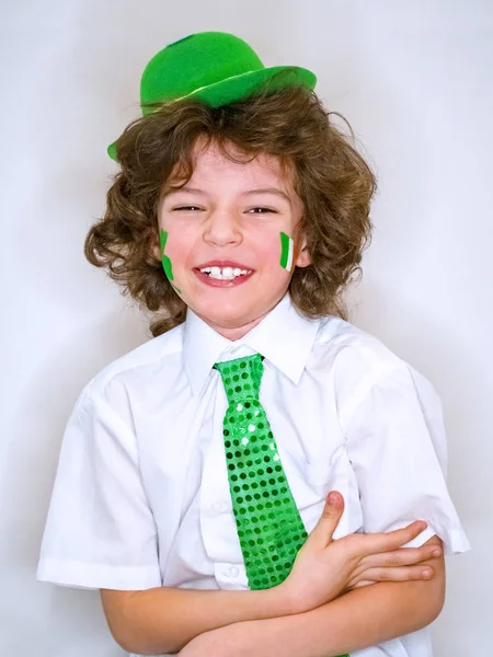 Spansktalande barn pojke att ha kul under Saint Patrick firandet över en ljus bakgrund. Jag leende en pojke med gröna shamrock och irländska flaggan på min kind. Patrick's Day firande. — Stockfoto