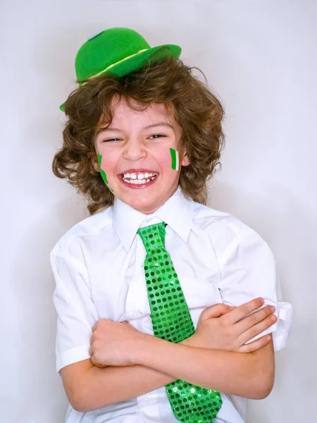 Spansktalande barn pojke att ha kul under Saint Patrick firandet över en ljus bakgrund. Jag leende en pojke med gröna shamrock och irländska flaggan på min kind. Patrick's Day firande. — Stockfoto