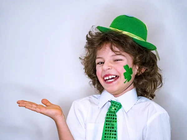 Lockiga barn pojke att ha kul under Saint Patrick firandet över en ljus bakgrund. Jag leende pojke med en grön shamrock på min kind som håller en imaginär ämne i min hand. Kopiera utrymme — Stockfoto