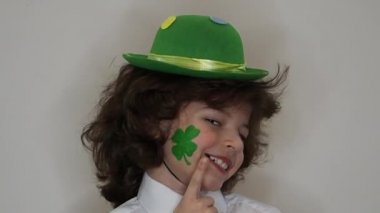 Çocuk kutlayan St. Patrick's günü onun makyaj gösterilen. Bir küçük, düzgün vücutlu erkek onun yanağına yonca bir yaprak şeklinde bir çizim, onun parmak işaret eder. ağır çekim