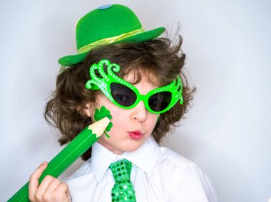 Komik St Patricks günü yeşil bir şapka giymiş küçük çocuk çarpıcı. Kendini ifade. Genç çocuk kendisi üzerinde büyük yeşil pencil.light arka planı olan bir yonca çizim.