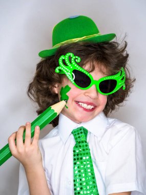 Komik St Patricks günü yeşil bir şapka giymiş küçük çocuk çarpıcı. Kendini ifade. Genç çocuk kendisi üzerinde büyük yeşil pencil.light arka planı olan bir yonca çizim.
