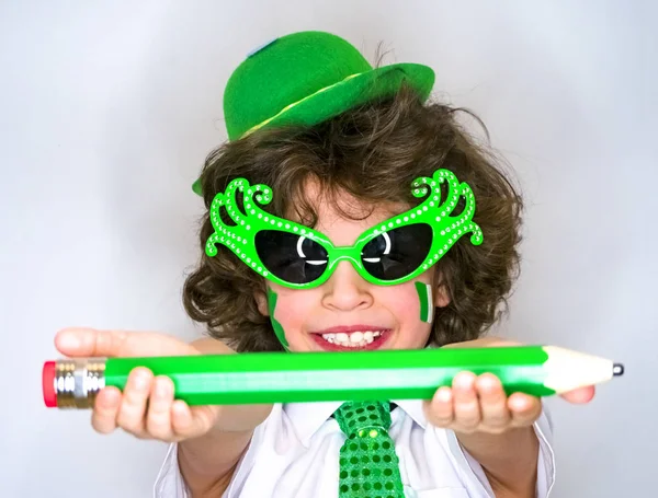 面白い聖パトリック日の見事な緑の帽子を身に着けている男の子 こぼれるような笑顔を点滅する彼の手の中の大きな緑色の鉛筆でポーズ中子 明るい背景 — ストック写真