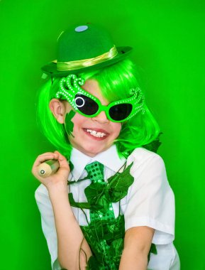 Komik St Patricks Günü çarpıcı küçük yeşil saç peruk. Elinde bir yeşil kalem ile poz, dişlek bir gülümseme yanıp sönen komik çocuk. yeşil arka plan