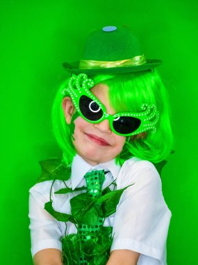 Çocuk kutlayan St. Patrick's günü onun makyaj gösterilen. Küçük bir gülümseyen çocuk yeşil karnaval aksesuarları kameraya bakıyor. yeşil arka plan
