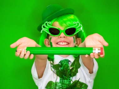 Komik St Patricks günü yeşil bir şapka, karnaval gözlük ve bir kravat giyen küçük çocuk çarpıcı. Komik çocuk onun elinde büyük bir yeşil kalem ile poz