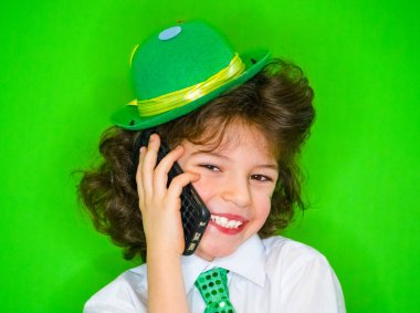Komik St Patricks Günü küçük çocuk bir yeşil şapka ve yonca, telefonda konuşurken onun yanaklarda İrlanda bayrağı giyiyor. Son derece heyecanlı ve eğlenceli bir çocuk için iyi haber telefon dinleme