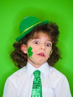 Çocuk çok şaşırır. Sevimli çocuk çocuk eğleniyor Saint Patrick kutlamalar sırasında yeşil bir arka plan üzerinde. ağzı açık şokta. Aziz Patrick günü. Tatminsizlik ve hayal kırıklığı kavramı.