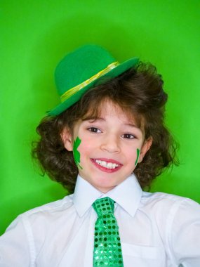 İspanyol çocuk çocuk eğleniyor Saint Patrick kutlamalar sırasında yeşil bir arka plan üzerinde. Yeşil yonca ve İrlanda bayrağı yanakları üzerinde küçük bir çocuk. Aziz Patrick günü kutlamaları.