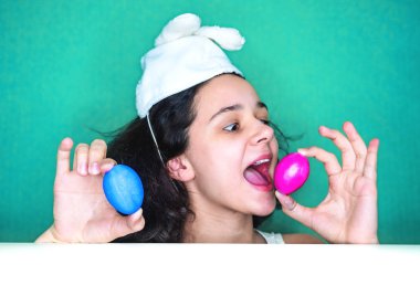 Kadın holding yumurta. Paskalya bunny kulaklar bir sürpriz yüz, korkuyor ve heyecanlı korku ifadesi ile şok korkmuş giyen genç esmer kadın.