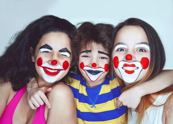Дві підліткові сестри і маленький брат в ролі клоунів позує в студії — стокове фото