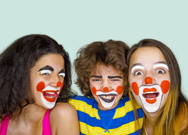 Twee tiener zusjes en een broertje in de rol van clowns poseren in de studio — Stockfoto