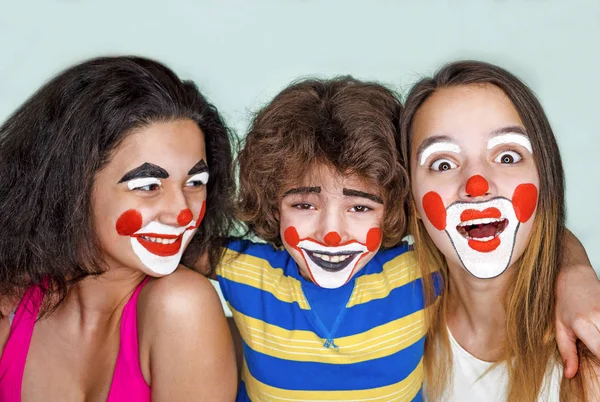 Twee tiener zusjes en een broertje in de rol van clowns poseren in de studio — Stockfoto