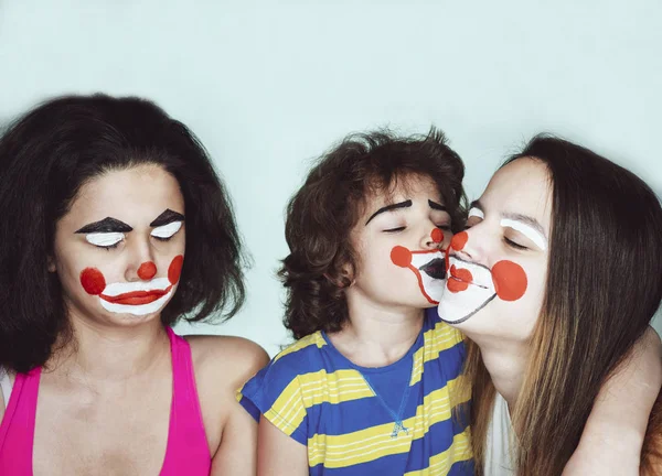 Twee tiener zusjes en een broertje in de rol van clowns poseren in de studio. Jaloezie concept. — Stockfoto