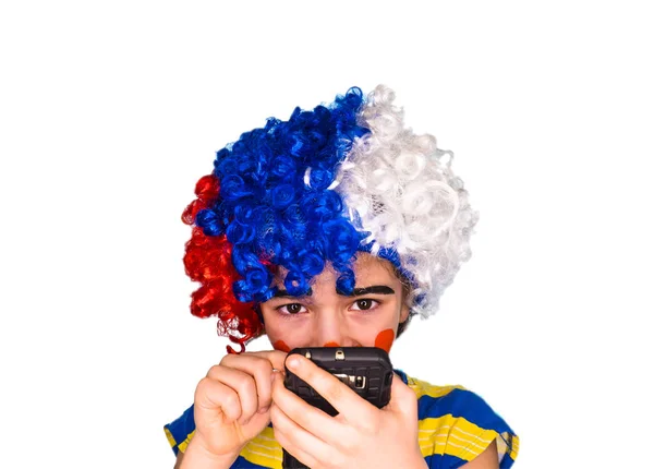 Portret van grappige clown kind met mysterieuze, sluwe blik houden smartphone en tekst te typen. Pantomime concept. expressie. emoties. April Fool's Day, 1 April. Geïsoleerd op wit — Stockfoto
