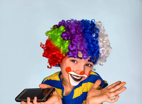 Portré boldog a vicces bohóc gyerek gazdaság smartphone, és élvezi a jó hír. Pozitív és a kifejezés concept.pantomimic kifejezés. érzelmek. Bolondok napja, április 1. — Stock Fotó