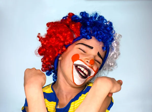 Divertente parrucca clown bambino godendo di una buona battuta avendo una risata abbondante con la bocca aperta e gli occhi chiusi mentre si allontana dalla fotocamera . — Foto Stock
