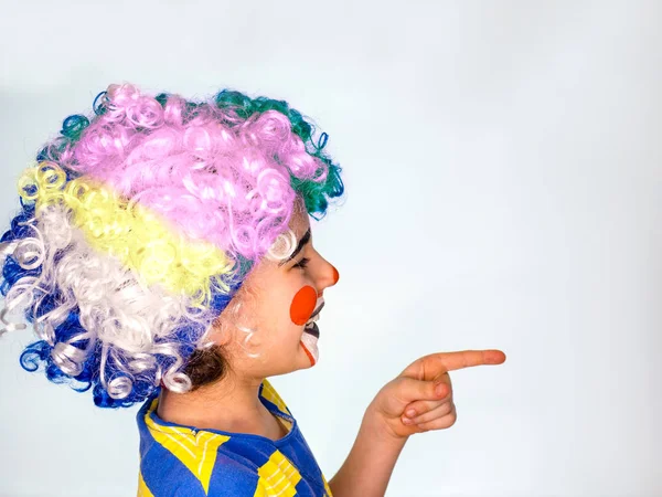 Knappe kleine jongen lacht en punten vinger. In profiel. kleine schattige jongen met facepaint als clown, pantomime expressie. emoties. April Fool's Day, 1 April — Stockfoto
