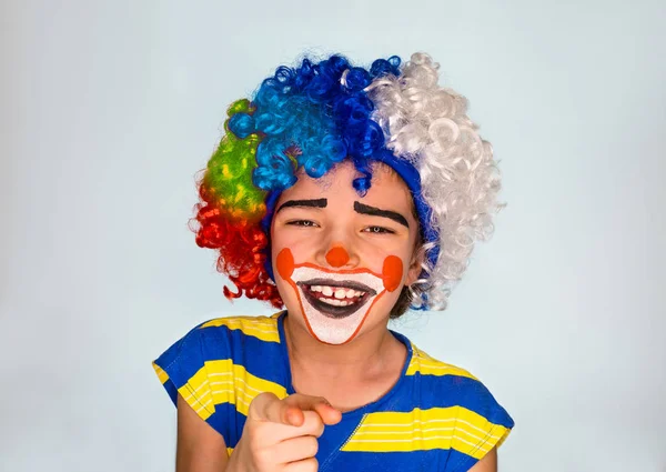 Guapo niño se ríe y señala con el dedo. pequeño niño lindo con pintura facial como payaso, expresión pantomímica. emociones. Día de los Inocentes, 1 de abril — Foto de Stock