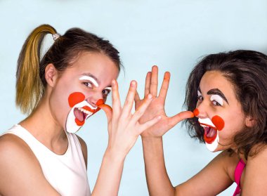 İki genç esmer t-shirt ve boyalı yüzler ile şaka yollu uzun burunları ile onların parmak palm göster. Gri izole. Nisan aptal gün aile kutluyor.