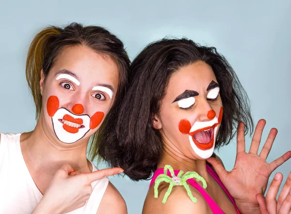 Ragazza gioiosa vedendo come sua sorella era spaventata dal suo ragno giocattolo sulla spalla. La tradizione di celebrare il giorno del concetto di sciocco. Isolato su sfondo chiaro . — Foto Stock