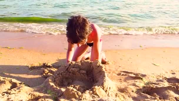 ビーチに座っていると 砂の城の建物の小さな男の子のスローモーション — ストック動画