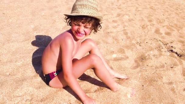 ビーチに座っていると 砂で遊ぶ男の子のスローモーション — ストック動画