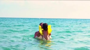 Baba ve oğlu can yeleği gündüz denizde oynarken yavaş hareket
