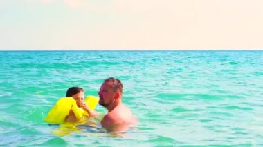 Baba ve oğlu can yeleği gündüz denizde oynarken yavaş hareket