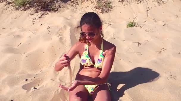 慢动作年轻女孩坐在海滩上玩沙子 — 图库视频影像