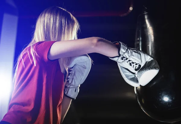 Woman hitting the boxing heavy bag in the gym. Hard mixed martial arts training