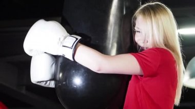 Güzel kadın Boxer spor salonunda egzersiz. Yorgun terli kadın sarılma bir punç çantası