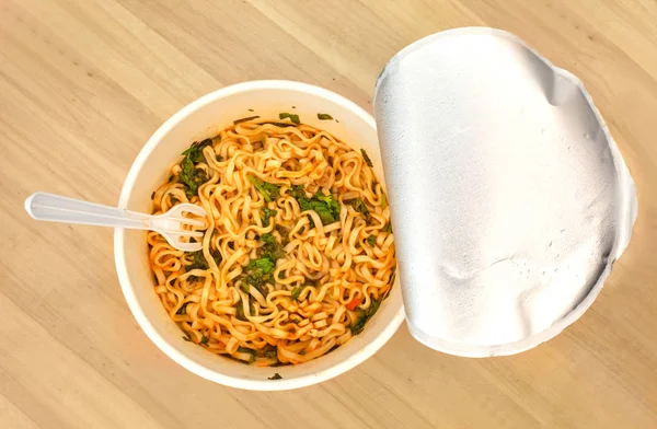 Instant noodle. noodle soup in a cup, view from above. Instant noodles are sold in a precooked and dried noodle block, with flavoring powder and,or seasoning oil.