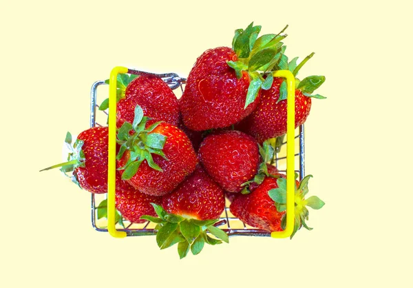 Self-service supermarket shopping basket with fresh strawberries, grocery products on a light background.Top view.