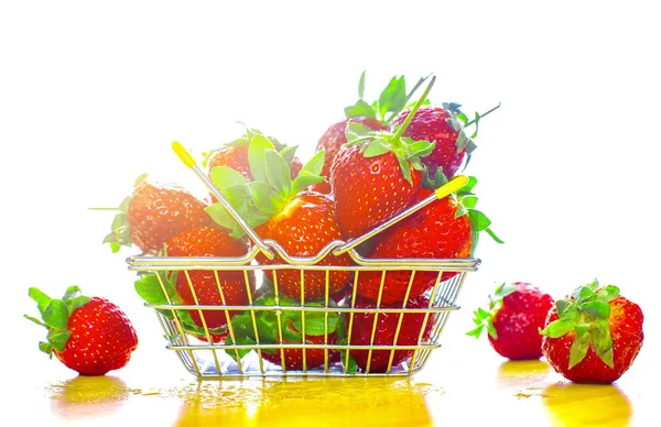 Self-service supermarket shopping basket with fresh strawberries, grocery products on a light background.