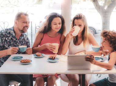 Kahvaltı ve tablet kullanarak mutlu bir aile. Mutlu bir adam ve internet, kullanarak seyir perde için üç çocukları gülümseyen kafe, dijital tablet olan büyük bir şirket online satın
