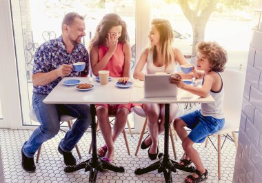 Kahvaltı ve tablet kullanarak mutlu bir aile. Mutlu bir adam ve internet, kullanarak seyir perde için üç çocukları gülümseyen kafe, dijital tablet olan büyük bir şirket online satın