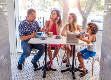 Kahvaltı ve tablet kullanarak mutlu bir aile. Mutlu bir adam ve internet, kullanarak seyir perde için üç çocukları gülümseyen kafe, dijital tablet olan büyük bir şirket online satın