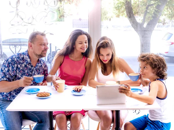 Kahvaltı ve tablet kullanarak mutlu bir aile. Mutlu bir adam ve internet, kullanarak seyir perde için üç çocukları gülümseyen kafe, dijital tablet olan büyük bir şirket online satın