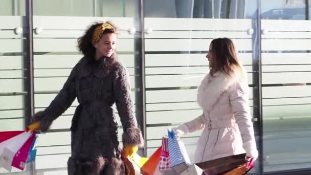 两个女孩穿着冬装在户外散步 手里拿着购物袋 现代城市背景 慢动作 — 图库视频影像