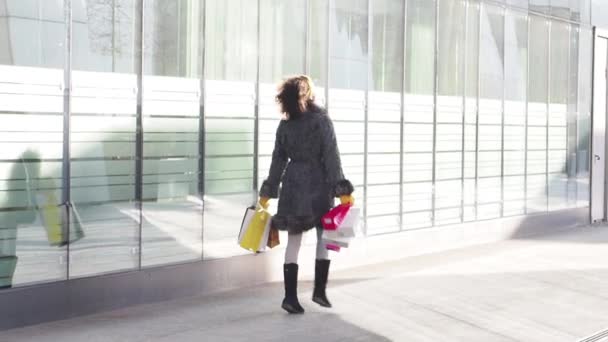 美容女孩在冬天的衣服走户外与购物袋在手中 现代城市背景 慢动作 — 图库视频影像