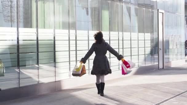 手に買い物袋を持って屋外を歩く冬服の美少女 近代的な都市の背景 スローモーション — ストック動画