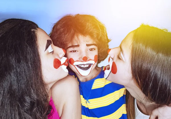 两个十几岁的姐妹和一个小弟弟在小丑的角色中摆出鲜艳多彩的背景 家庭亲情概念 — 图库照片