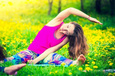 Kız germe egzersizleri pratik. Güzel genç kadın parkta yeşil çim üzerinde egzersiz germe yapıyor.