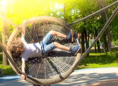 Neşeli çocuk Swing-yuva sallanan. Açık havada okul öncesi için eğlence