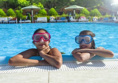 Gündüz leri aqua parktaki yüzme havuzunda oynayan iki mutlu çocuk. Dışarıda eğlenen insanlar. Dost aile ve yaz tatili konsepti.